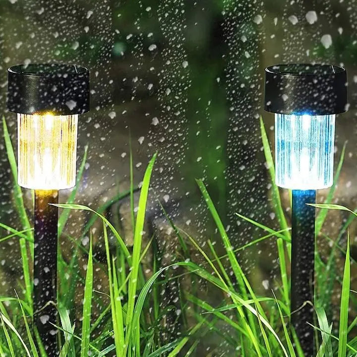Two solar-powered garden lights in grass with raindrops on a blurred background