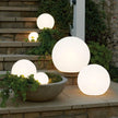 Glowing spherical outdoor lights on a stone ledge with plants.