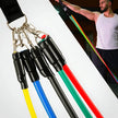 Resistance bands with colorful handles on a white background, with a person exercising in the background.