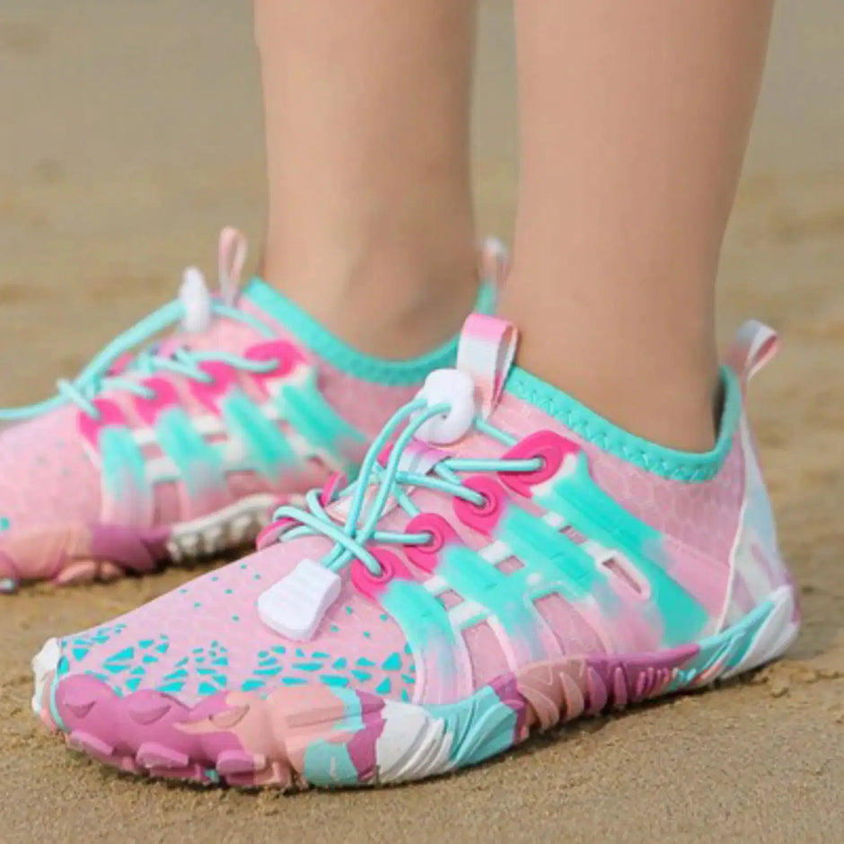 Pink and teal water shoes on a sandy background