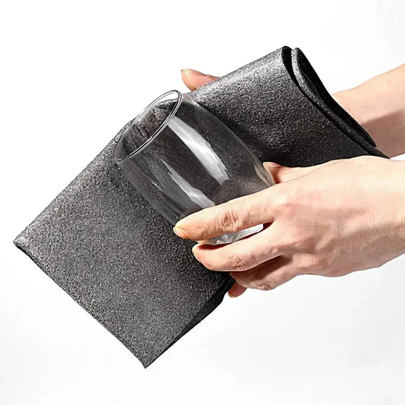 Person cleaning a glass with a black scrubber on a white background