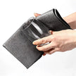 Person cleaning a glass with a black scrubber on a white background