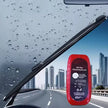 Red oil film cleaning brush held against a car windshield with raindrops and cityscape background