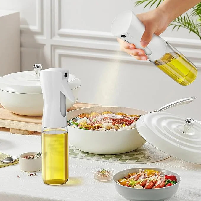 Person using an olive oil sprayer over a salad on a kitchen counter.