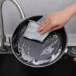 Person cleaning a frying pan with a sponge in a kitchen setting