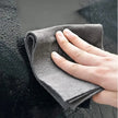 Person cleaning a car window with a gray microfiber cloth