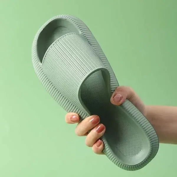 Hand holding a green slipper against a green background