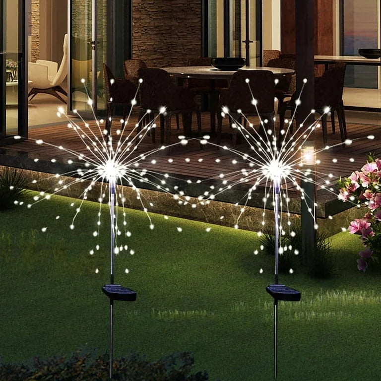 Solar garden lights resembling fireworks on a lawn with a dining area in the background