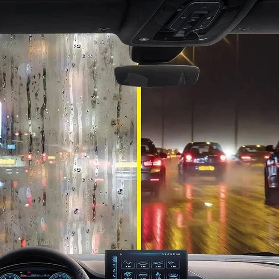 Car interior with raindrops on the windshield and a view of traffic at night.