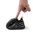 Small black and gray sneaker being pointed to by a finger on a white background