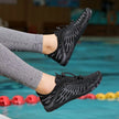 Black water shoes worn by a person with gray leggings, above a pool.