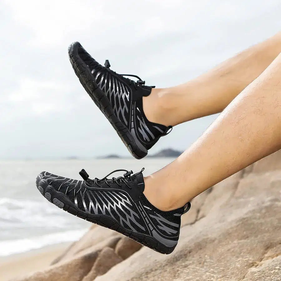 Black water shoes worn by a person on a beach
