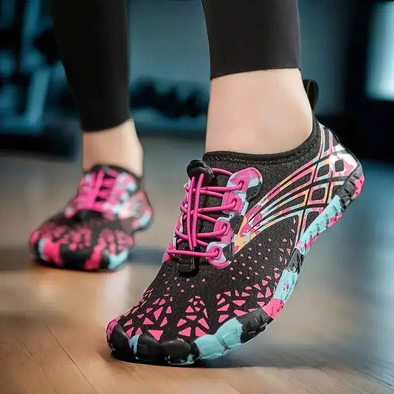 Colorful water shoes with pink laces on a wooden floor.
