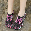 Black and pink patterned shoes on a concrete surface