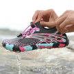 Colorful water shoe with pink laces being worn, with water dripping from it against a natural background.