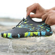 Person wearing a colorful water shoe with water dripping from it, standing on a rocky surface.