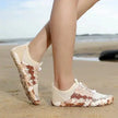 Beige and brown patterned shoes on a sandy beach with ocean view