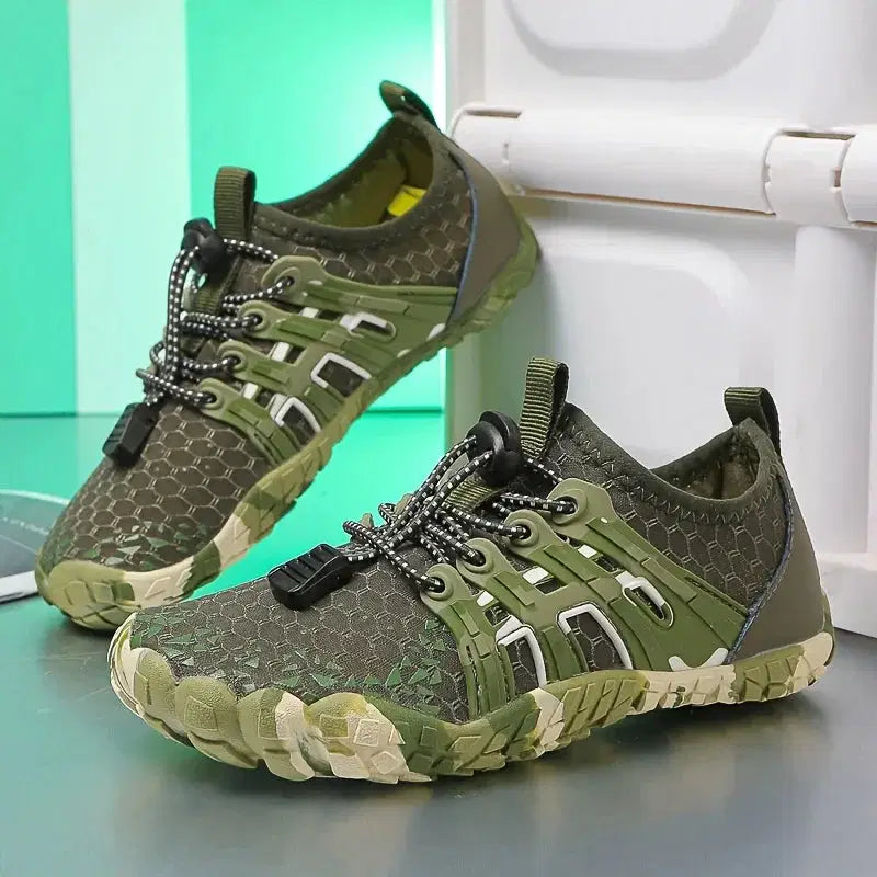 Green and gray outdoor shoes on a light blue surface with a white background