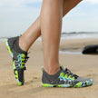 Person wearing gray and green water shoes on a beach