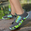 Gray and green water shoes on a person's feet with a natural background