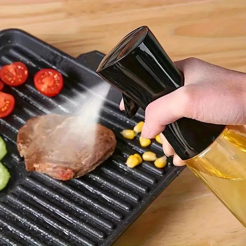 Person using a black oil sprayer on a grill with vegetables and meat.