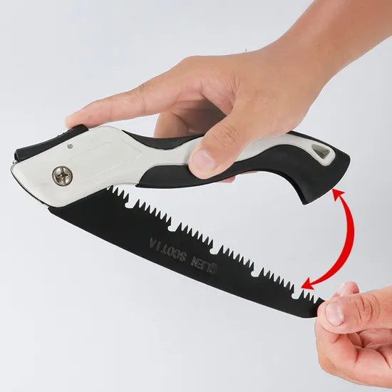Hand holding a folding saw with a white blade and black handle, on a light gray background.