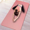 Person stretching on a pink yoga mat with a wooden floor background
