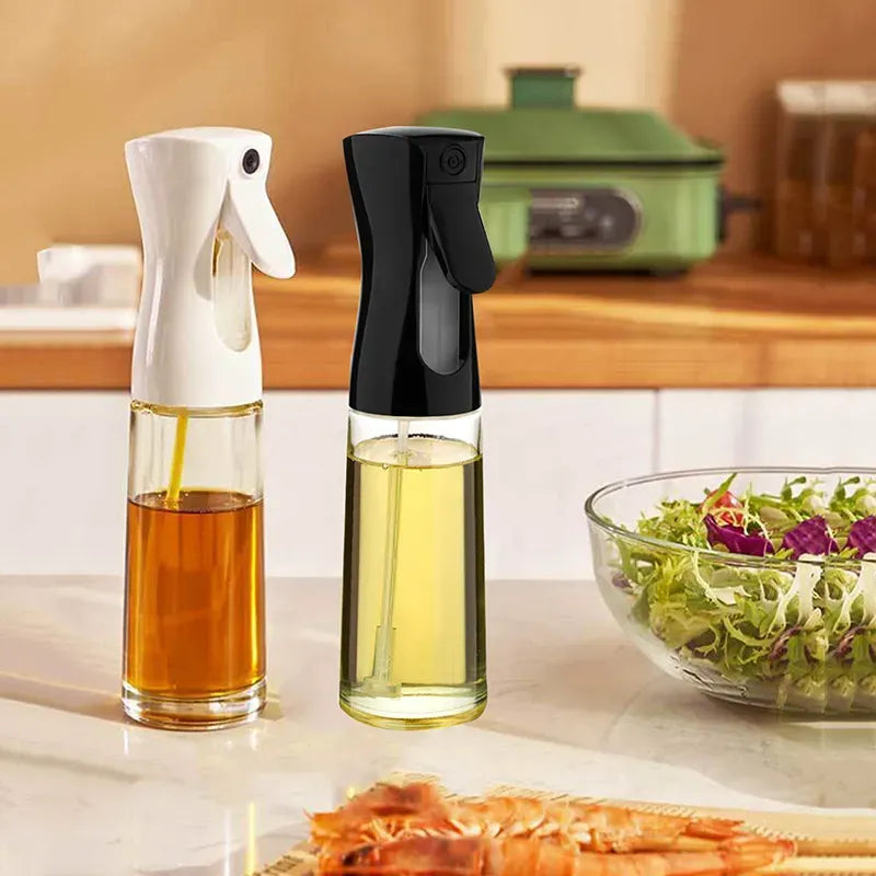Two oil sprayers with different oils on a kitchen counter with a salad and shrimp in the background.