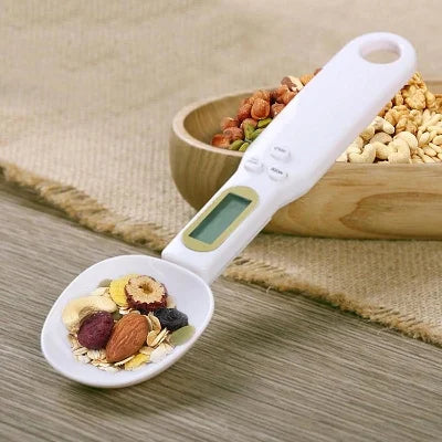 Digital measuring spoon with a bowl of mixed ingredients on a wooden surface