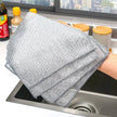 Metal mesh scrubber held over a kitchen sink with window view in the background