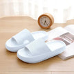 White slippers on a wooden surface with a clock and magazine in the background