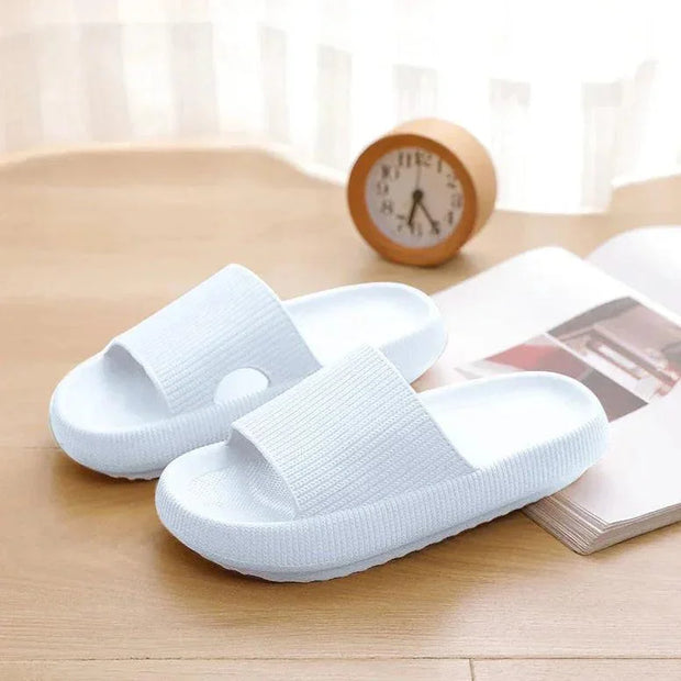 White slippers on a wooden surface with a clock and magazine in the background