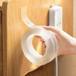 Hand holding a roll of white tape against a wooden surface with a power strip.