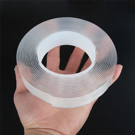 Hand holding a roll of clear adhesive tape against a black background