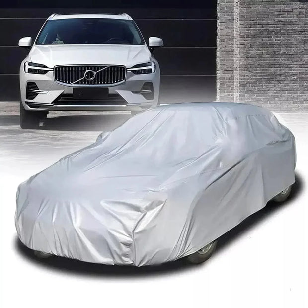 White car covered with a car cover in front of a gray building.