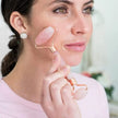 Woman using a rose gold facial roller on her face