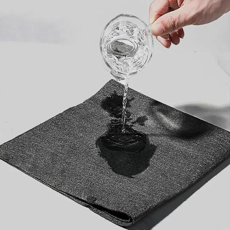 Glass of water being poured onto a black mat with a white background