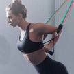 Woman exercising with resistance bands against a plain background