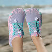 Colorful water shoes on a beach with ocean in the background