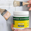 Person applying polyurethane waterproof coating to a surface with a brush, showing a container of the product.
