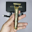 Gold and bronze electric razor held by a hand with a blurred background