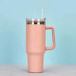 Pink insulated tumbler with a handle on a light blue background