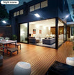 Modern house with a wooden deck and open patio area at night.