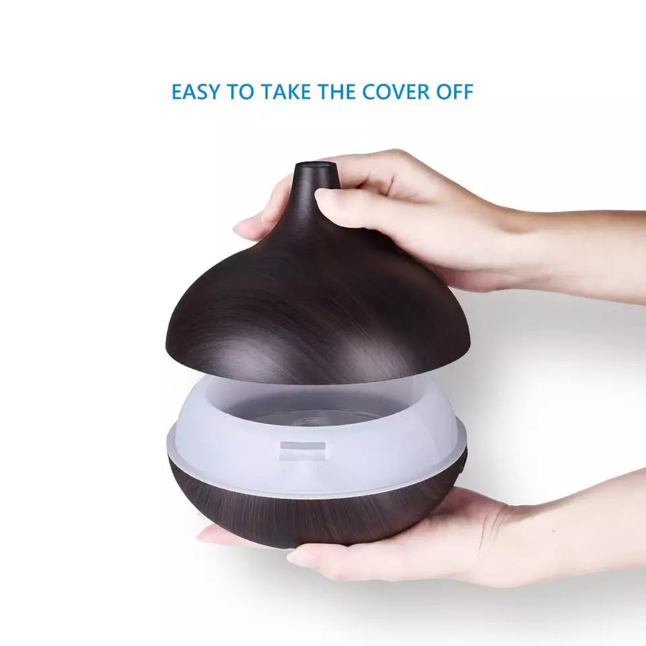 Hand lifting the cover of a dark brown diffuser on a white background