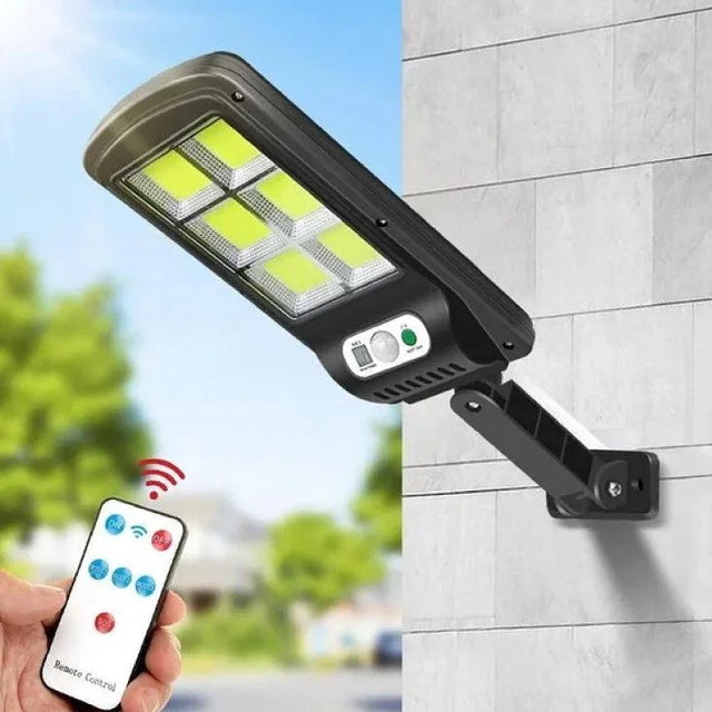 Solar street light attached to a wall with a remote control held by a hand.