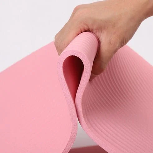 Pink yoga mat being held by a hand on a light gray background