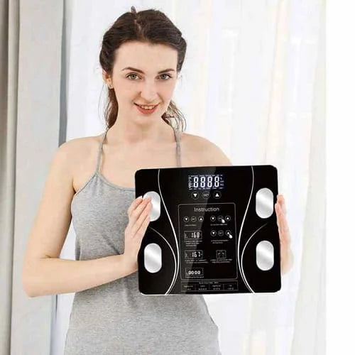 Woman holding a digital body fat scale against a white curtain background
