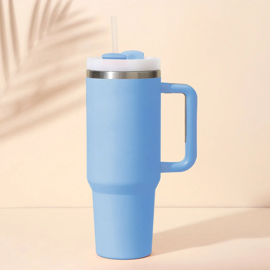 Blue insulated tumbler with handle on a beige background