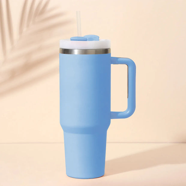 Blue insulated tumbler with handle on a beige background