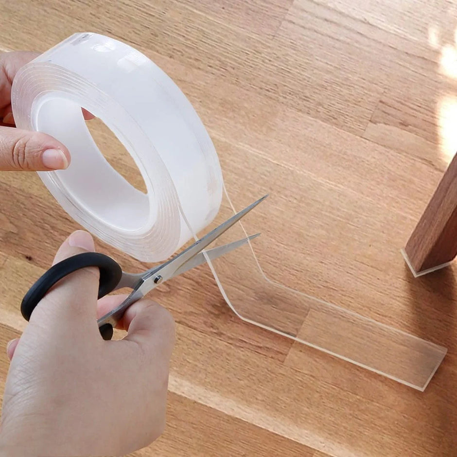 Person cutting clear tape with scissors on a wooden surface